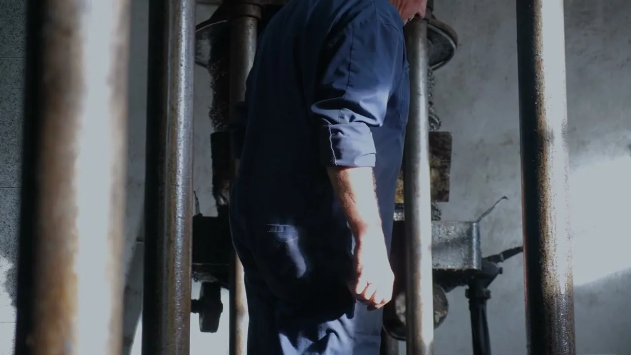 A worker leaning into the iron press.